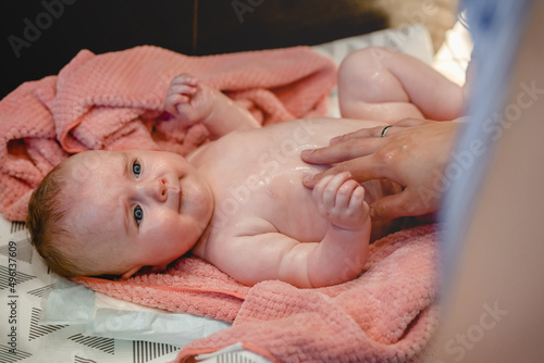 Newborn, infant, baby girl in towel after bath. Cute baby looks at mom. Love and care, happiness and joy. Miracle of motherhood, happy family concept.
