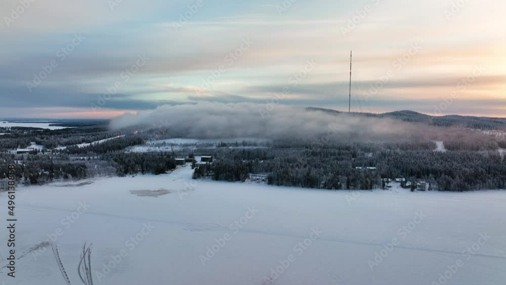 Aerial drone view over a lake towards the foggy Vuokatti mountain, sunset in Finland Aerial drone view over a lake towards the foggy Vuokatti mountain, sunset in Finland