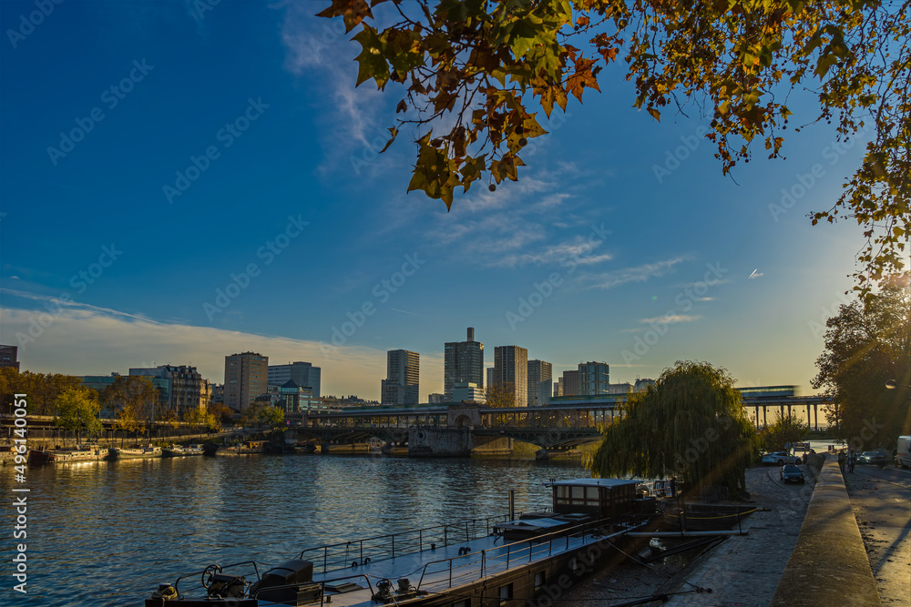 Fototapeta premium Wide View of Bir Hakeim Bridge in Paris Under Sun With Fall Colors Trees Seine River and Boats