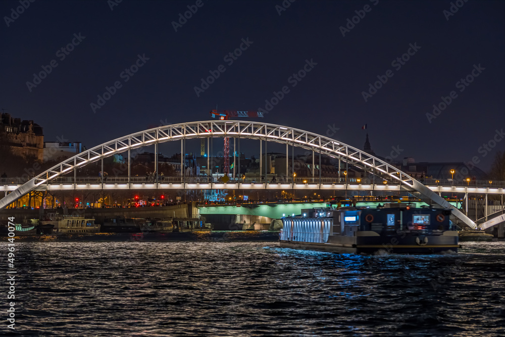Enlightened Pedestrian Bridge at Night in Paris Seine River and Tourists Cruises