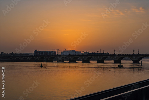 Fototapeta Naklejka Na Ścianę i Meble -  Twilight Over Bordeaux and Stone Bridge With Tramway and Orange Sky