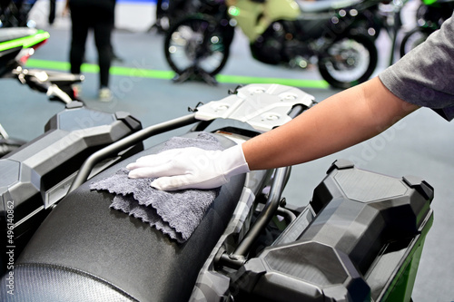 Closeup of Hand of Asian Male Employee using microfiber cloth cleaning motorcycle in a car wash shop in Thailand.