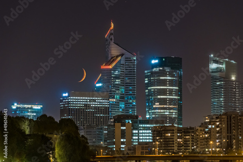 Trees and Enlightened Towers of La Defense District at Night With Crescent Moon