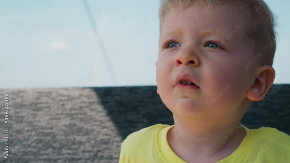 Cute toddler child boy with chubby cheeks in yellow t-shirt yawns in gondola riding cable way at mountain resort close view slow motion Cute toddler child boy with chubby cheeks in yellow t-shirt yawns in gondola riding cable way at mountain resort close view slow motion