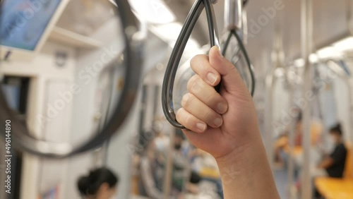 Close-up of Hands holding handrail or grip straps in metro train,public subway transportaion train. photo