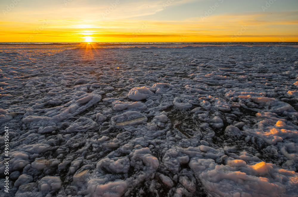 Close-up of snow and ice on sea shore at winter. Sunset sky.