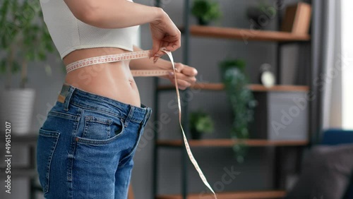 Unrecognizable woman body oversize jeans dieting results abdominal muscle waist size measurement
