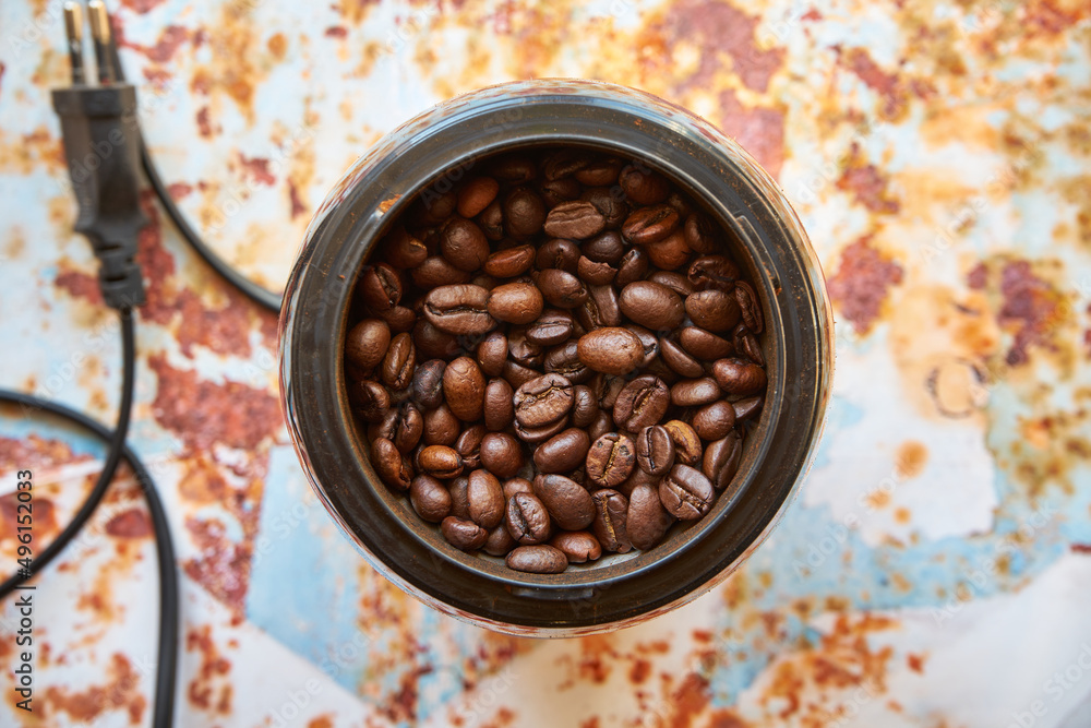 Naklejka premium ziarna kawy w czarnym elektrycznym młynku do kawy 