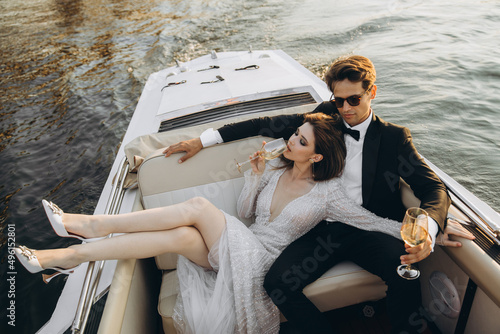 Stylish young bride and groom huging and kissing on yacht © ALEXSTUDIO