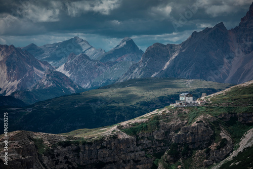 Rifugio Auronzo mountain hut during day in front of Dolomite Alps mountains at Three Peaks in Italy, clouds in sky.