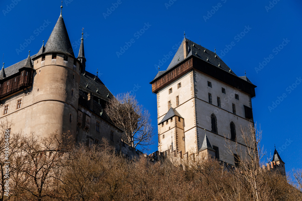 Karlstejn, Bohemia, Czech Republic, 12 March 2022: old royal medieval gothic castle with tower founded by king Charles IV, blue sky at sunny spring day, famous landmark, battlements fortified walls