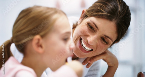 Making sure her smile is as bright as her future. Shot of a beautiful young mother watching her daughter brush her teeth in the bathroom at home.