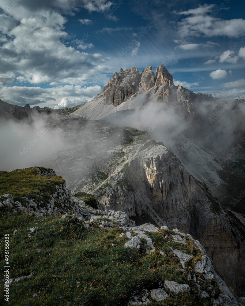 Mountain Paternkofel with fog in Three Peaks Nature Reserve in the Dolomite Alps in South Tyrol with clouds in blue sky.