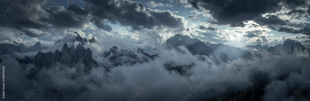 Mountain panorama with low clouds around mountain summits in Three Peaks Nature Reserve in the Dolomite Alps in South Tyrol with clouds in dark sky.