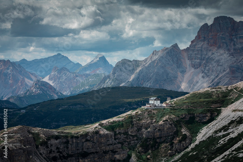 Rifugio Auronzo mountain hut during day in front of Dolomite Alps mountains at Three Peaks in Italy, clouds in sky.