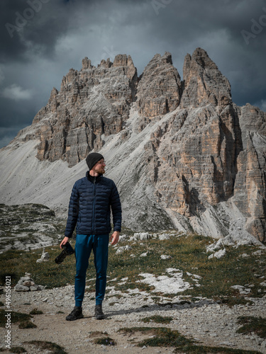 Man taking photos with camera with view to Paternkofel mountains peak in the Dolomite Alps in South Tyrol with dramatic dark sky, Three Peaks Nature Reserve, Italy.