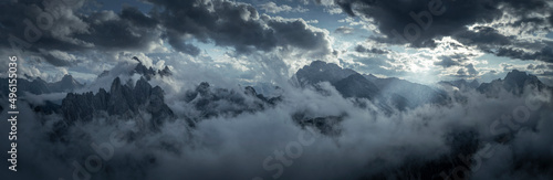 Mountain panorama with low clouds around mountain summits in Three Peaks Nature Reserve in the Dolomite Alps in South Tyrol with clouds in dark sky.
