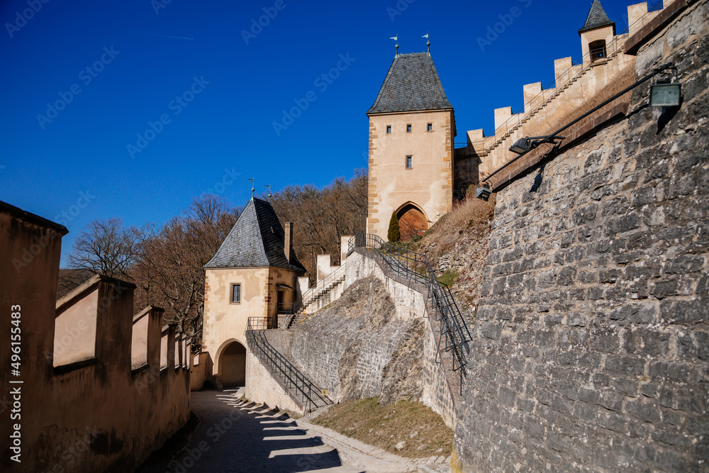 Karlstejn, Bohemia, Czech Republic, 12 March 2022: old royal medieval gothic castle with tower founded by king Charles IV, blue sky at sunny spring day, famous landmark, battlements fortified walls