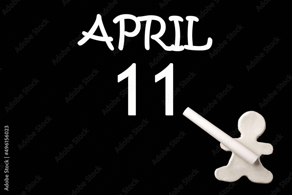 A small white plasticine man writing the date 11 April on a black board. Business concept. Education concept. A small white plasticine man writing the date 11 April on a black board. Business concept. Education concept.