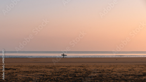 The pastel pinks and blues glow above a lone surfer at the water's edge on Belhaven Bay to the south of the North Sea
