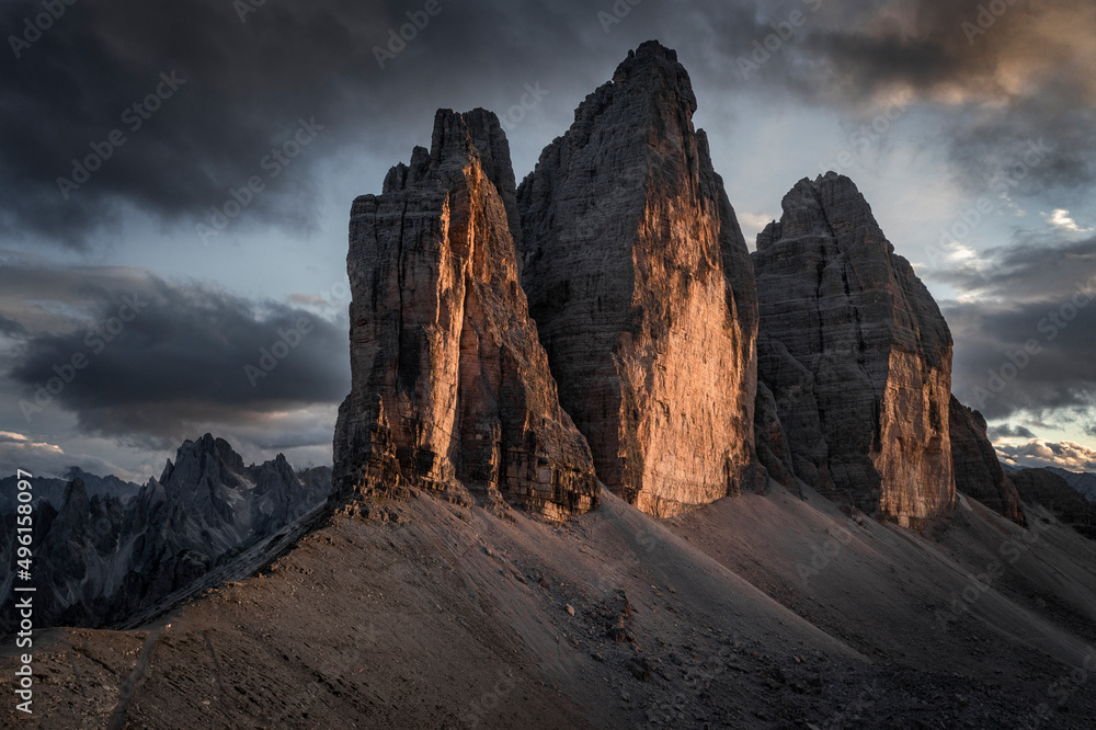 Three Peaks mountain summits in the Dolomite Alps in South Tyrol with clouds during sunset.