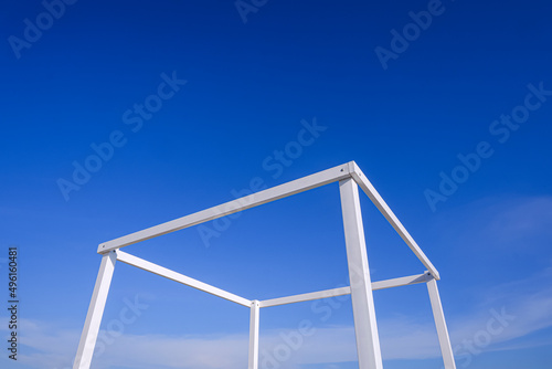 Simplicity summer background of white transparent cubic stand structure for travel photography against blue sky background