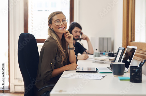 Pursuing some more of her big goals. Portrait of a confident young businesswoman working in an office with her colleague in the background.
