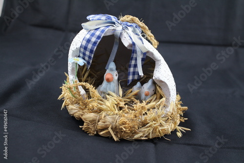 Ostermotive auf schwarzem Hintergrund. Osterdekorationen in Nahaufnahme. Weidenkranz mit bunten Eiern. Arrangement in Eierschale auf Stroh. Tonei mit Huhn darin. Symbole des Lebens und des Glücks. photo