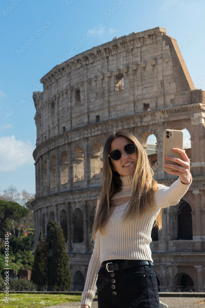 Young happy woman taking a selfie with the phone in front of the Roman colosseum