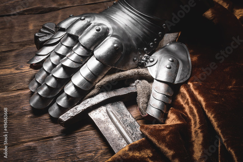 Ancient rusty sword and armor gloves on the table close up background Fototapeta