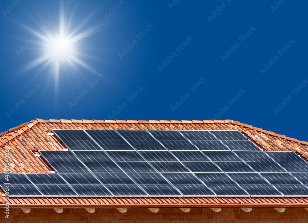 Roof with solar panels on blue sky with sun rays, copy space Roof with solar panels on blue sky with sun rays, copy space