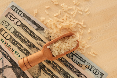 Rice scattering in a wooden spoon on a light board. U.S. dollars. The product is dietary, the benefits of proper nutrition. Export, import - concept.