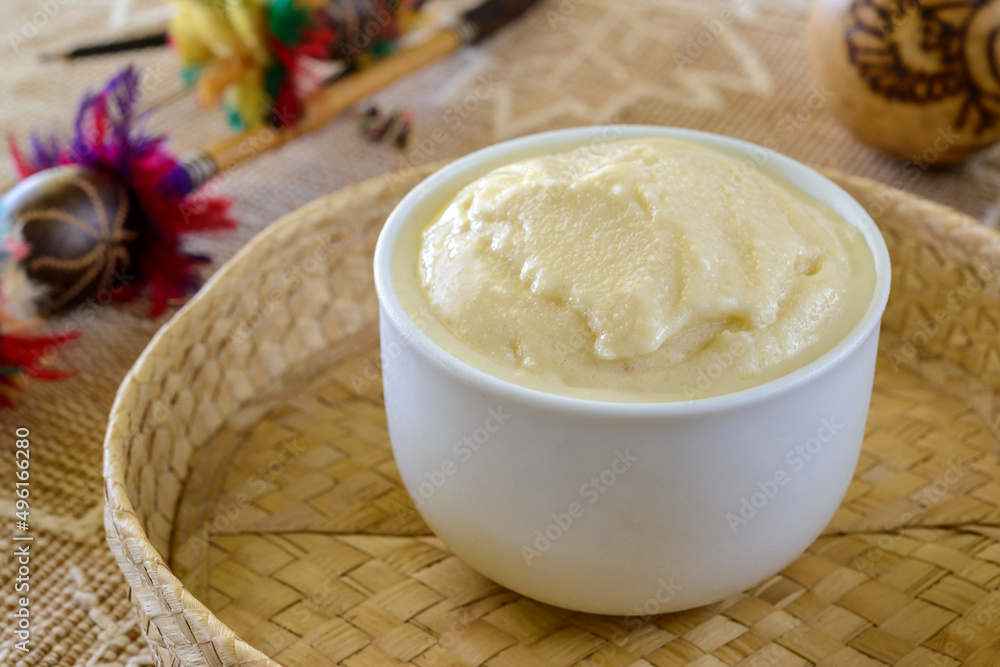 Cupuacu ice cream, fruit from the Brazilian Amazon, in a white bowl on a table with blurred Amazonian handicrafts in the background. Cupuacu ice cream, fruit from the Brazilian Amazon, in a white bowl on a table with blurred Amazonian handicrafts in the background.