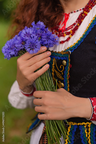hands in traditional belarus clothing with cornflowers