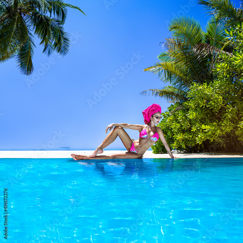 Sexy bikini body woman playful on paradise tropical beach having fun playing splashing water on Maldives. Beautiful fit body girl on travel vacation. Elegant model near the pool.