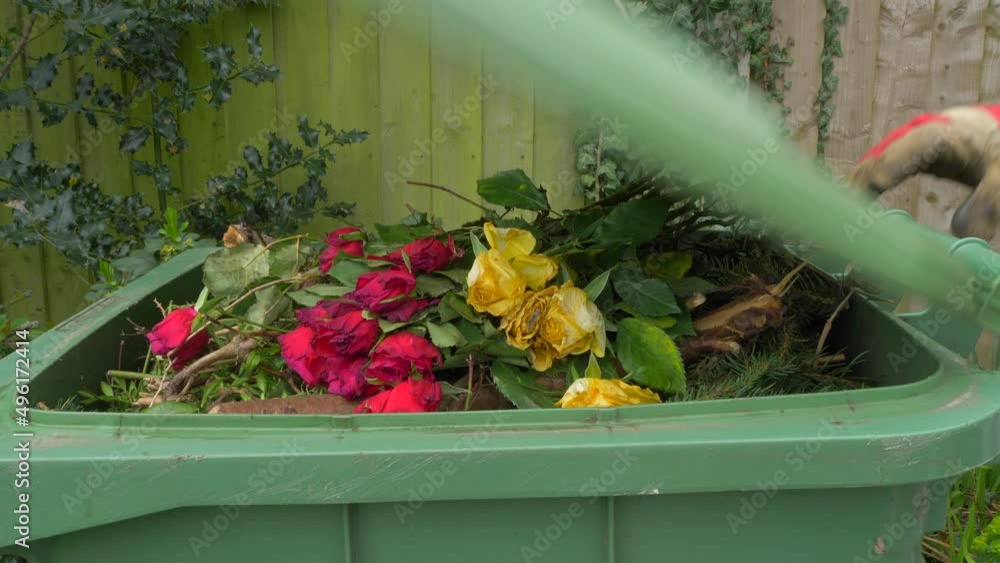A person’s gloved hands throwing some dead flowers on the very top of