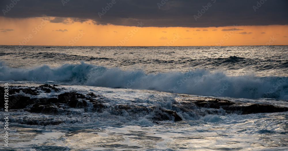 Windy waves splashing on the rocky coast at sunset. Stormy sky in winter Windy waves splashing on the rocky coast at sunset. Stormy sky in winter