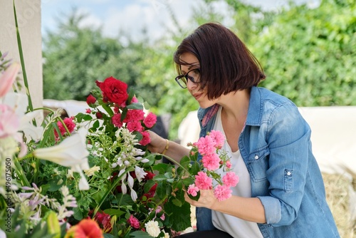 Woman florist making flower arrangement in basket outdoor.