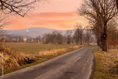 Sunset evening in the Pogórze Izerskie area in Poland in the early spring landscape with some trees and lonely road