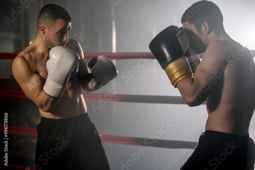 Two professional young muscular shirtless male boxers fighting in a boxing ring. High quality photography. © herraez