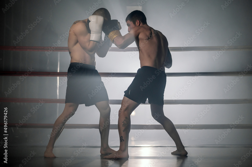 Obraz premium Two professional young muscular shirtless male boxers fighting in a boxing ring. High quality photography.