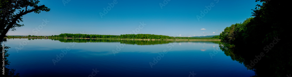 Panoramic view of a calm lake on a sunny summer day Panoramic view of a calm lake on a sunny summer day