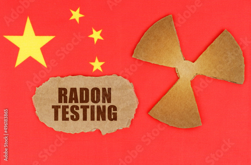 On the flag of China, the symbol of radioactivity and torn cardboard with the inscription - Radon Testing