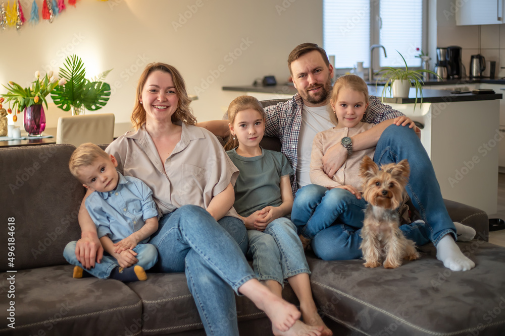 family portrait. family photo in which mom, dad, daughters, son and dog are smiling and hugging on the couch in a cozy homely atmosphere. selective focus family portrait. family photo in which mom, dad, daughters, son and dog are smiling and hugging on the couch in a cozy homely atmosphere. selective focus