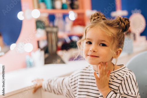 Portrait of a little beautiful girl with a stylish hairstyle in a beauty salon, expressing happiness of the pretty kid