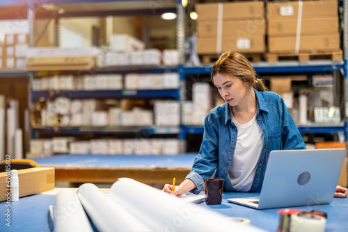 Woman using laptop at warehouse 