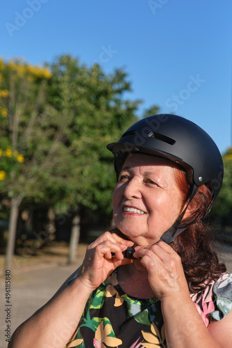 Happy mature latin woman smiling putting on a helmet. Active life, road safety. © Carolina Jaramillo
