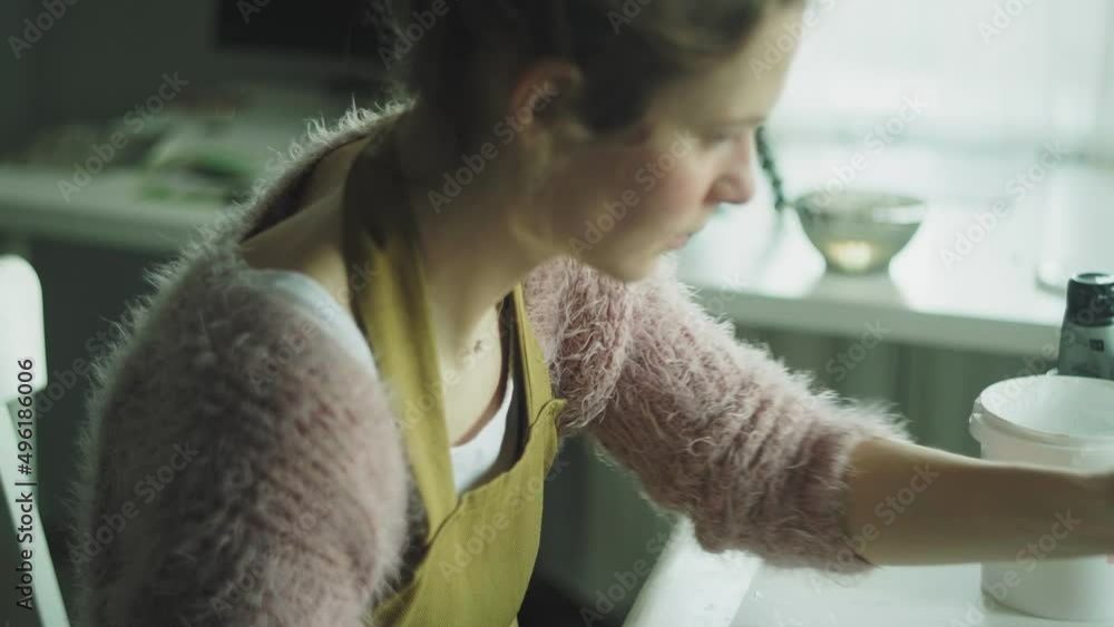 A woman paints a wooden part of a wooden product with a brush. Business idea for a home workshop A woman paints a wooden part of a wooden product with a brush. Business idea for a home workshop