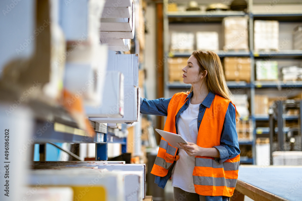 Woman with tablet in factory storehouse checking location of goods Woman with tablet in factory storehouse checking location of goods
