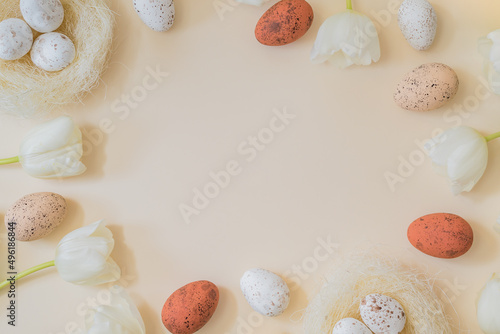 Flat lay easter composition with white tulips and easter eggs on a beige background